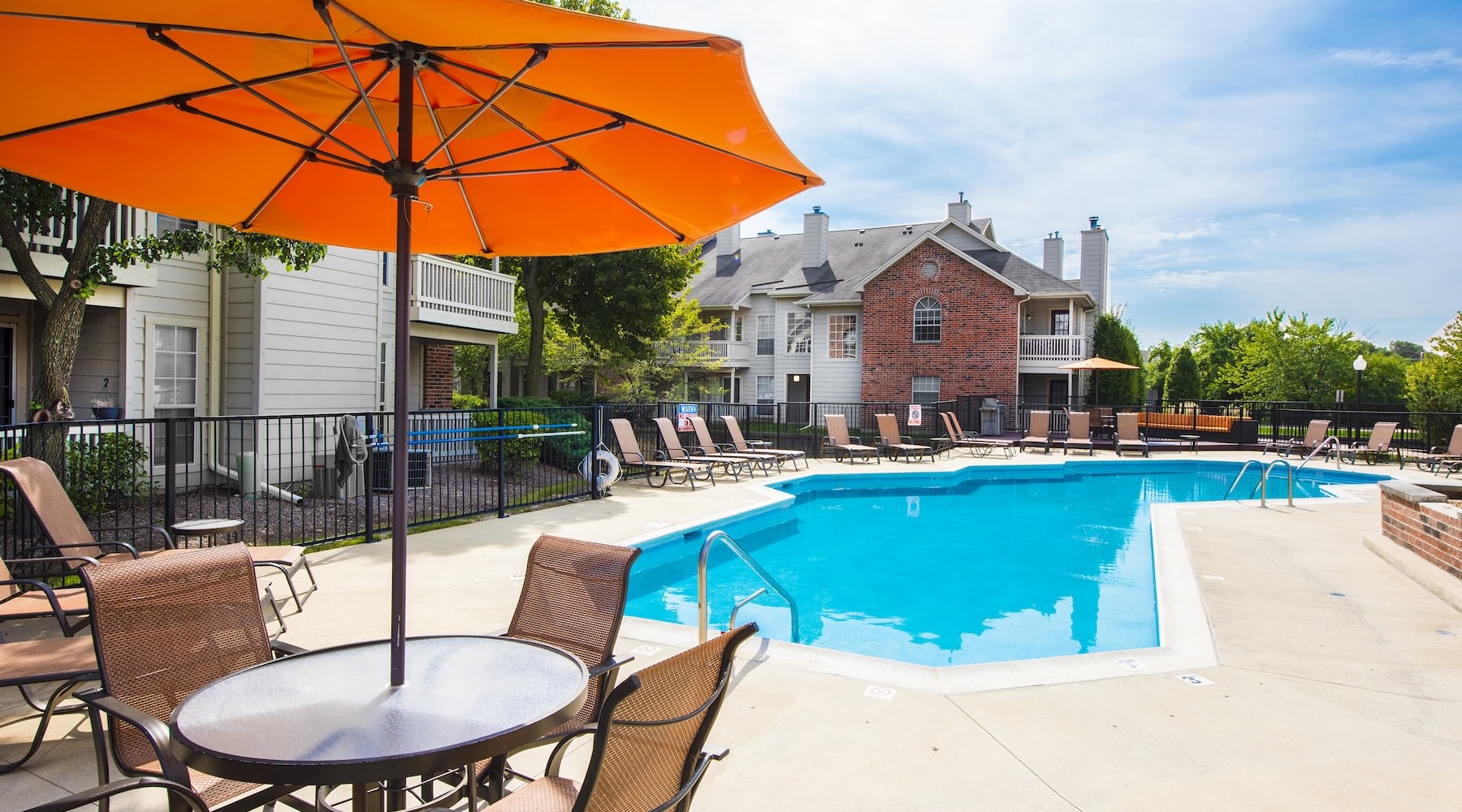 a swimming pool with a table, chairs and an umbrella