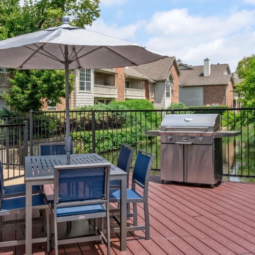a grill area with tables, chairs and an umbrella